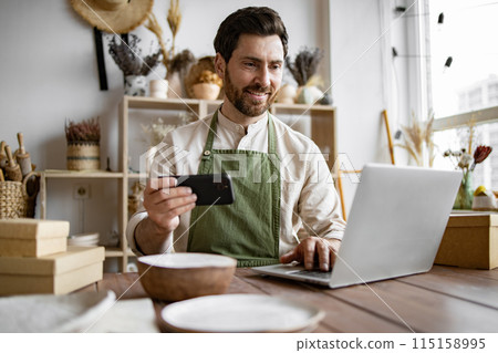 Positive manager of decorative clay store takes photo on phone for social media. Positive manager of decorative clay store takes photo on phone for social media. 115158995