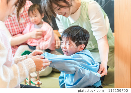A female nursery teacher changing clothes at a nursery school and a boy who is going through the "no" phase 115159790