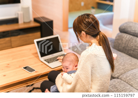 A young Asian woman working remotely while raising a child or holding a baby 115159797