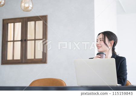 A woman looking up while using a computer in the office, holding a cup of coffee; bright image of job change, recruitment, etc.; copy space A woman looking up while using a computer in the office, holding a cup of coffee; bright image of job change, recruitment, etc.; copy space 115159843