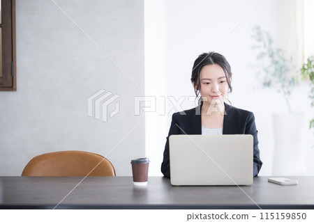 A business scene from the front of a woman using a computer in a beautiful backlit office, with copy space 115159850