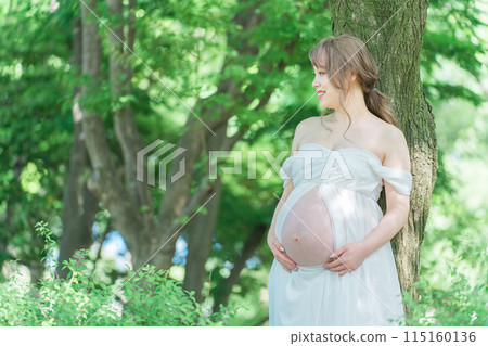 Asian pregnant women taking maternity photos (Sunlight filtering through foliage) 115160136