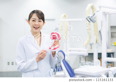 Dentist and dental hygienist giving tooth brushing instructions 115161133