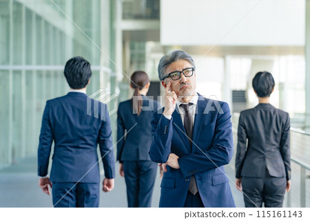 Senior male business person facing away from subordinates and worried 115161143