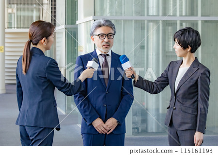 A middle-aged man being interviewed by the media 115161193