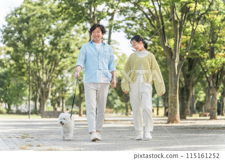 Parents and children, father, daddy and daughter (dog lovers) walking their dog in the park 115161252