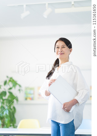 Senior woman standing with a laptop Senior woman standing with a laptop 115161650