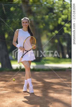 A woman is holding a tennis racket and standing on a tennis court A woman is holding a tennis racket and standing on a tennis court 115161694