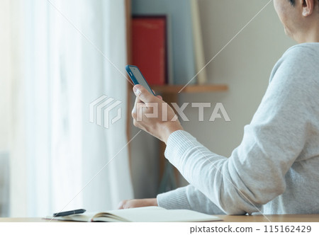 A middle-aged man checking his smartphone and notebook 115162429