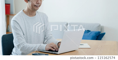 A middle-aged man thinking while looking at a computer A middle-aged man thinking while looking at a computer 115162574