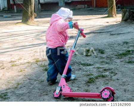 Little girl and her scooter. Little girl to drive a scooter to teach yourself 115162900