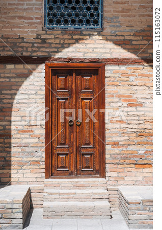 carved wooden door to Kukeldash Madrasah with traditional uzbek pattern decorated with oriental ornaments in Uzbekistan in Tashkent 115163072