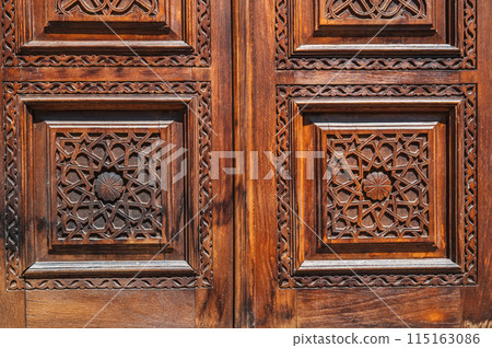 Oriental tajik kandakori patterns arabesque ornament on an old wooden carved door in Tajikistan close-up 115163086