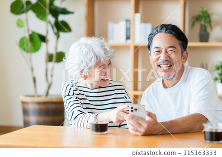 A senior couple looking at their smartphones together. 115163333