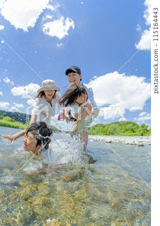 A family of four playing on a river in summer 115164443