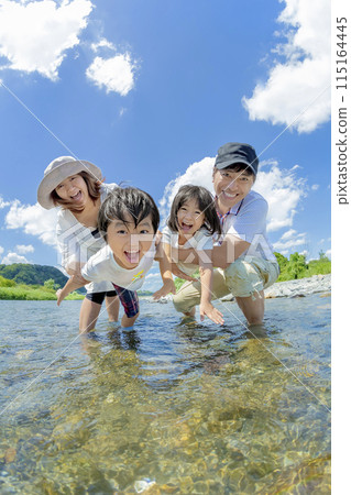 A family of four playing on a river in summer A family of four playing on a river in summer 115164445