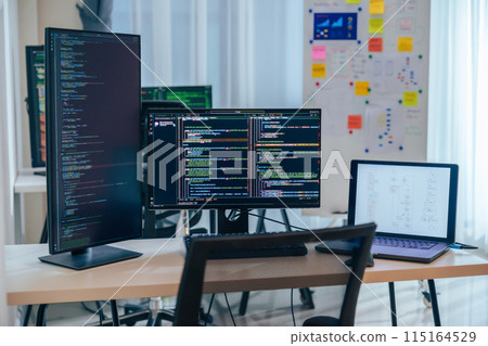 Software development office Workstation setup with multiple monitors displaying code and development diagrams during a nighttime coding session Software development office Workstation setup with multiple monitors displaying code and development diagrams during a nighttime coding session 115164529
