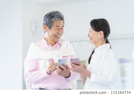 Active senior men and women having a conversation with smartphones 115164734
