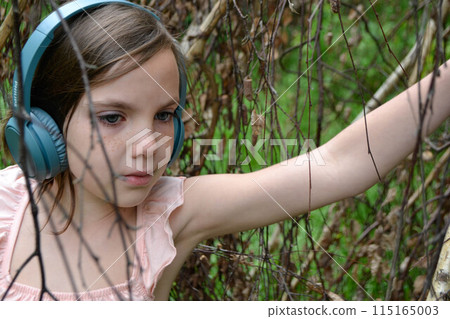 Relaxed woman lying on the grass listening to music with headphones in a park Relaxed woman lying on the grass listening to music with headphones in a park 115165003