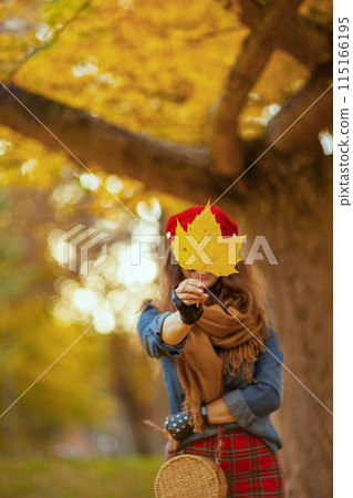 smiling stylish woman in jeans shirt and red hat 115166195