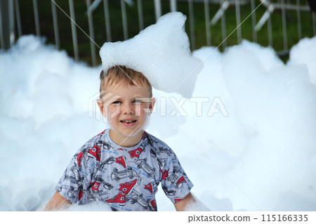 happy little boy with foam on his head, in wet clothes at a foam party happy little boy with foam on his head, in wet clothes at a foam party 115166335