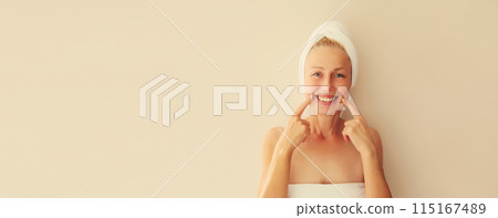 Happy smiling caucasian middle-aged woman points to her white clean teeth in the morning at home Happy smiling caucasian middle-aged woman points to her white clean teeth in the morning at home 115167489