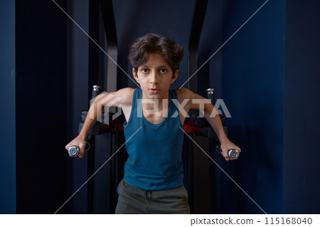 Sporty preteen boy training abs demonstrating strength and power Sporty preteen boy training abs demonstrating strength and power 115168040