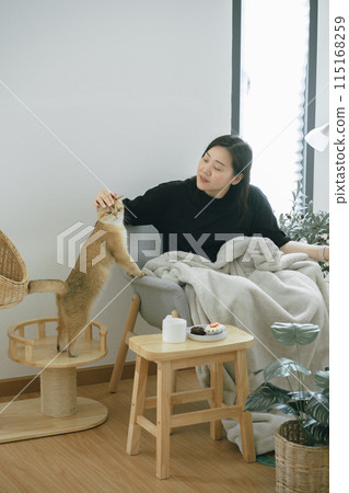 pet care concept with owner during read book and take coffee break and play with cat in livingroom pet care concept with owner during read book and take coffee break and play with cat in livingroom 115168259