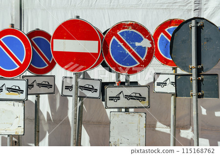Several large circular prohibitory road signs stand next to each other turned at different angles Macro 115168762