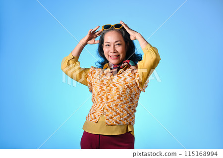 Cool and stylish asian senior woman with sunglasses and fashionable clothes on light blue background 115168994