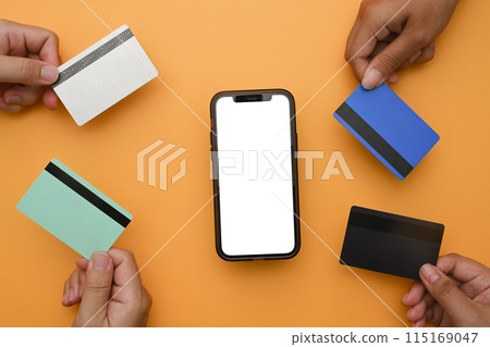 Mobile phone with blank screen and hands holding bank cards on yellow background. Modern payment systems concept 115169047