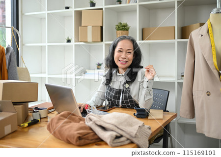 Happy middle age entrepreneurs checking online orders on laptop and preparing small parcel for postage Happy middle age entrepreneurs checking online orders on laptop and preparing small parcel for postage 115169101