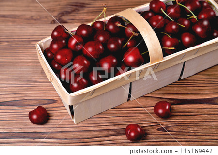 Ripe natural cherries, sweet cherries in a birch bark basket on a wooden background, close-up Ripe natural cherries, sweet cherries in a birch bark basket on a wooden background, close-up 115169442