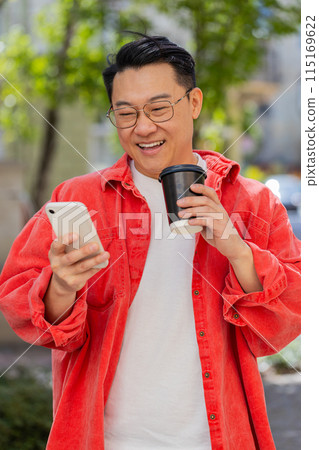 Happy Asian man enjoying drinking morning coffee hot drink, relaxing, taking a break on city street 115169622