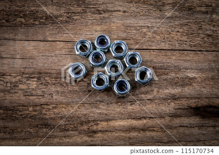 Stack of zinc plated self locking hexagon nuts on a dark wood texture background 115170734