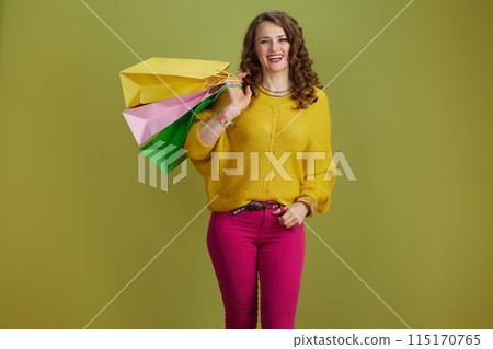 smiling trendy woman in yellow sweater against green background 115170765