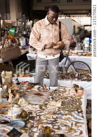 Man from Africa selects antiques at flea market 115170821