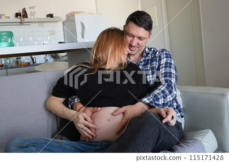 A loving couple embraces, their hands gently resting on her pregnant belly, sharing a tender moment of anticipation A loving couple embraces, their hands gently resting on her pregnant belly, sharing a tender moment of anticipation 115171428
