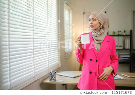 A woman in a pink jacket is holding a cup of coffee 115171678
