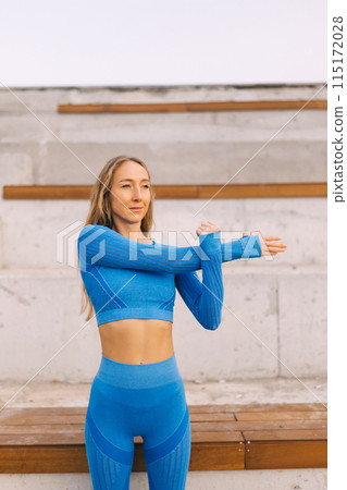 Young fitness woman in sports clothing making exercises in the street at sunny day. Young fitness woman in sports clothing making exercises in the street at sunny day. 115172028
