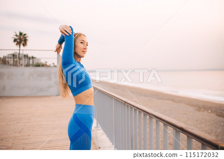 Young fitness woman in sports clothing making exercises in the street at sunny day. 115172032