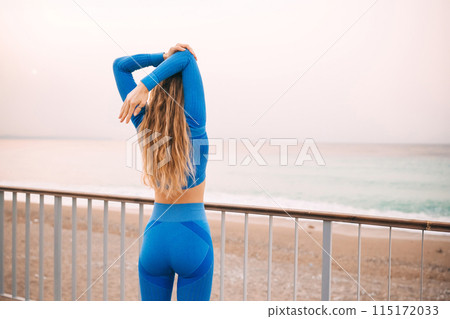 Young fitness woman in sports clothing making exercises in the street at sunny day. 115172033