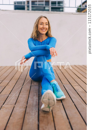 Young fitness woman in sports clothing making exercises in the street at sunny day. 115172035