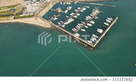 Aerial view of the port of Lake Garda. Yacht Club. Moored yachts and motorized private boats. The pier is made of wood. Beautiful clear water. Copy space. Italy, Peschiera del Garda, Lake Garda Aerial view of the port of Lake Garda. Yacht Club. Moored yachts and motorized private boats. The pier is made of wood. Beautiful clear water. Copy space. Italy, Peschiera del Garda, Lake Garda 115172682