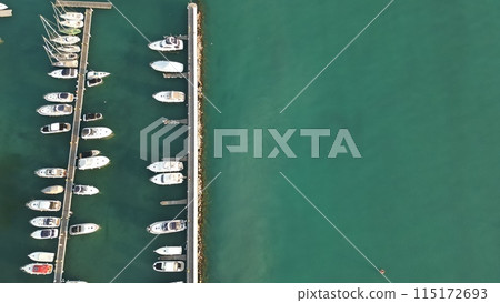 Italy, Peschiera del Garda, Lake Garda - Aerial view of the port of Lake Como. Yacht Club. Moored yachts and motorized private boats. The pier is made of wood. Beautiful clear water. 115172693