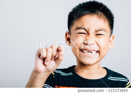 Child holds fallen baby tooth indicating good dental care. First tooth loss represents toddler growth joy and happiness. Children show teeth new gap, dentist problems 115173895