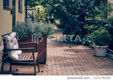 Stone one-storey minimalist house in the backyard with a small garden and a wooden bench where you can relax and sit. With space to copy. High quality photo 115174250
