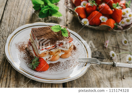 strawberry tiramisu served on a white plate and wooden background, decorated with flowers, Italian tiramisu dessert strawberry tiramisu served on a white plate and wooden background, decorated with flowers, Italian tiramisu dessert 115174328