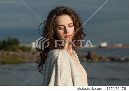 Romantic young woman model with brown hair and natural make-up walking along the shore of the resort Romantic young woman model with brown hair and natural make-up walking along the shore of the resort 115174476