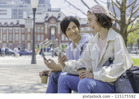 入境外國遊客夫婦坐在東京車站前,看著他們的智慧型手機 入境外國遊客夫婦坐在東京車站前,看著他們的智慧型手機 115175592